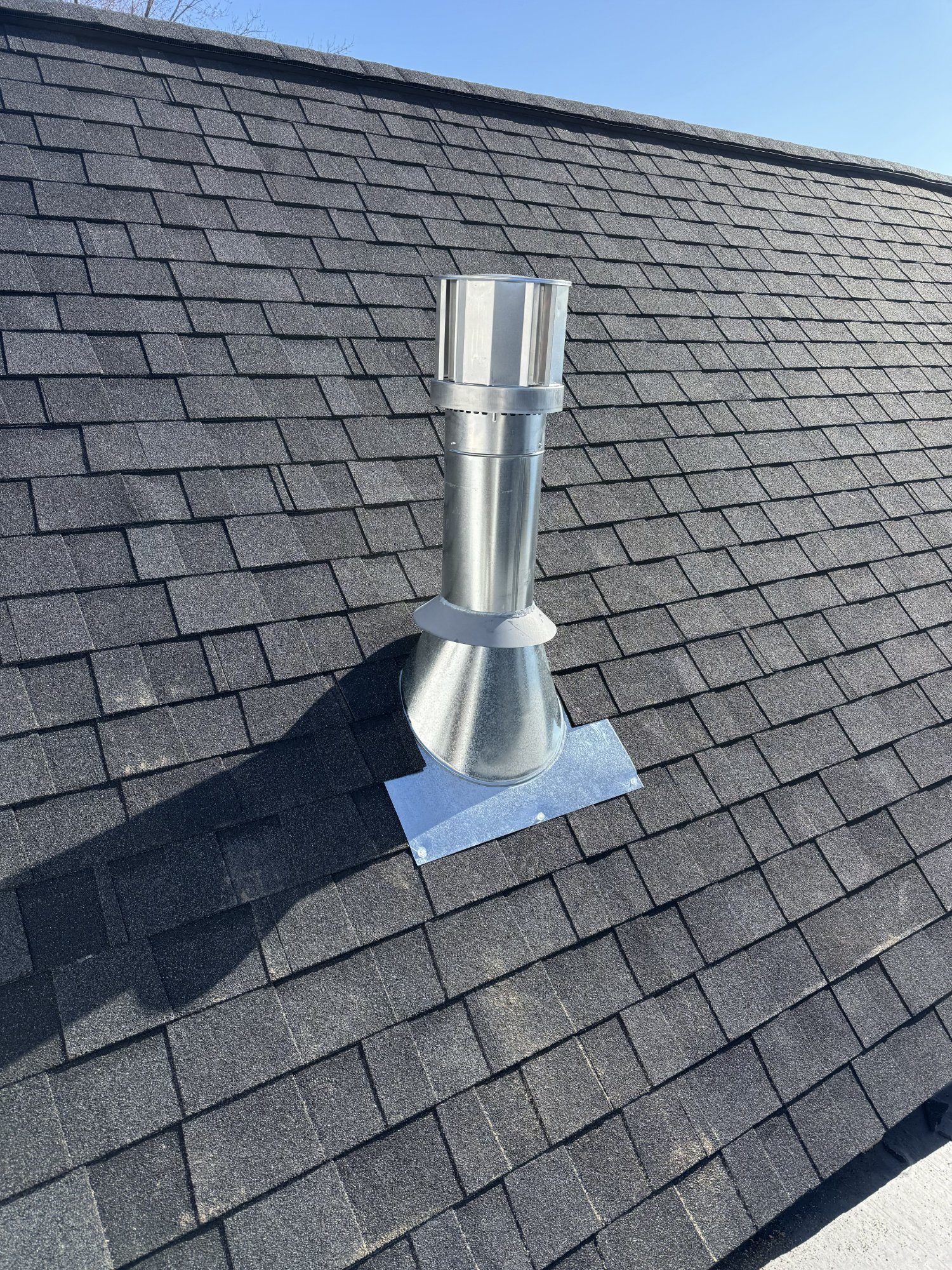 Stainless steel chimney cap with flashing on dark shingle roof — Wisconsin